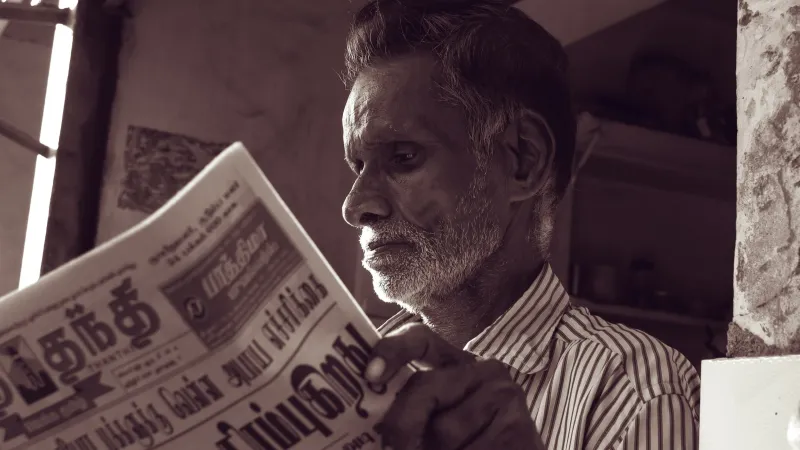 Man in black and white striped dress shirt reading newspaper