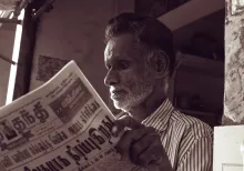 Man in black and white striped dress shirt reading newspaper