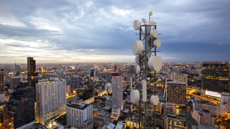 Telecom tower against a modern city at dusk